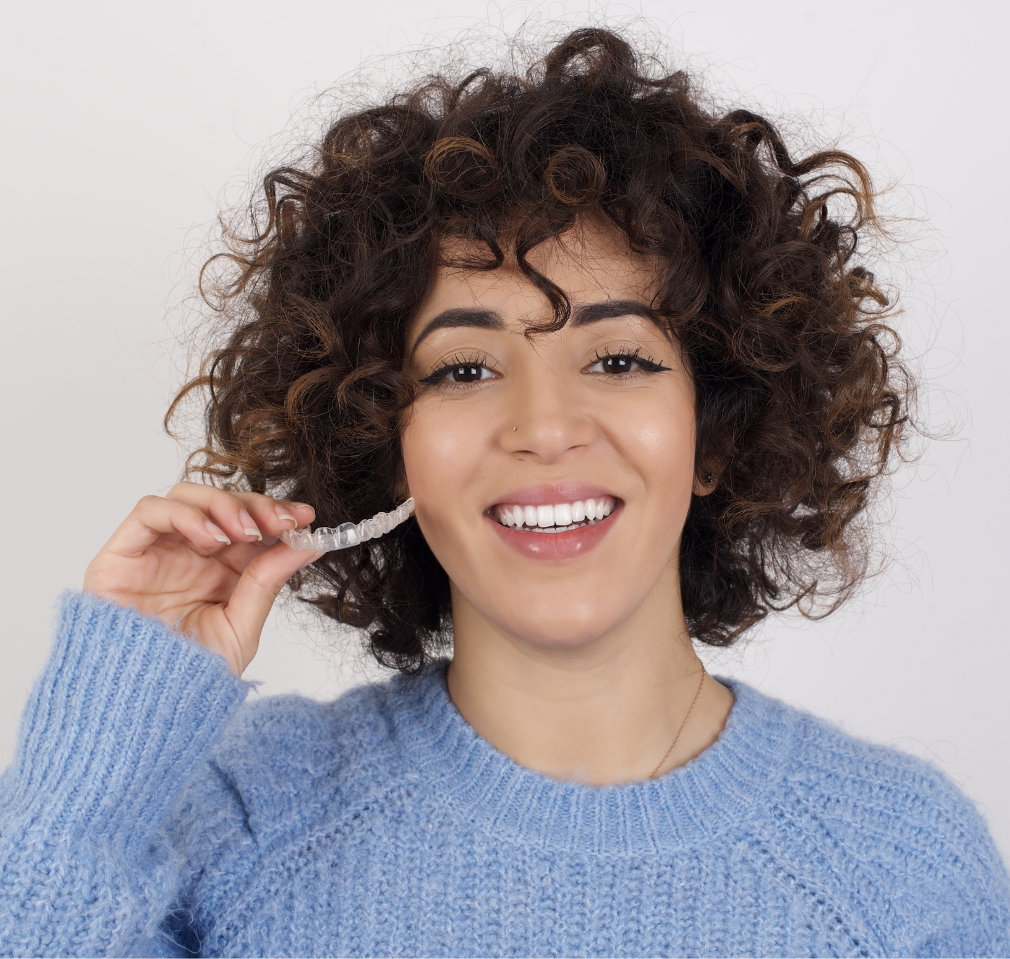 Invisalign NYC - Woman holding aligners.